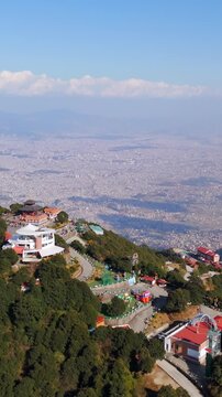 Aerial: Kathmandu city skyline under a clear blue sky with white clouds, Nepal