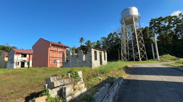 Horizontal ground level shot balancing water tank unfinished house greenery and clean residential houses in a peaceful village setting at Camella Homes Alfonso Cavite Philippines