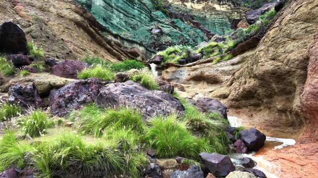 Stunning view of a waterfall cascading through the unique multicolored rocks of Los Azulejos de Veneguera after a storm in Mogan, Gran Canaria