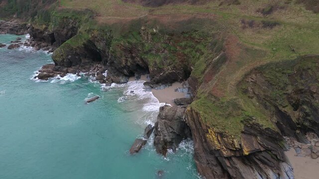 Aerial view of rugged coastline with turquoise sea, cliffs, and a small beach, showing the natural beauty of the landscape, Fowey, Cornwall, United Kingdom.