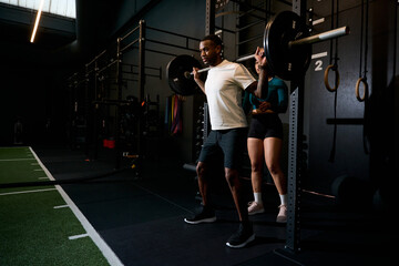 Fototapeta premium Man exercising squatting with barbell and personal trainer