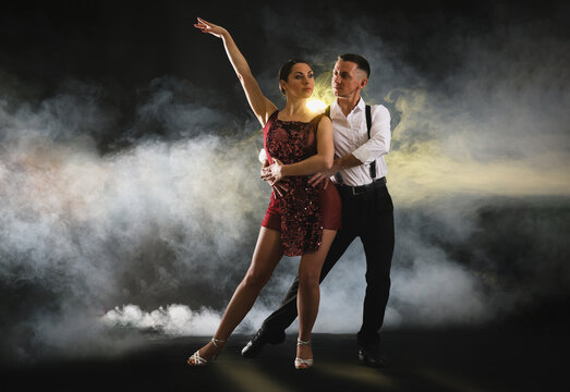 Couple of professional dancers on dark background with smoke