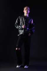 Naklejka premium Young man in stylish clothes and accessories in color light on black background