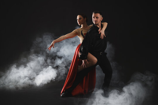 Couple of professional dancers on dark background with smoke