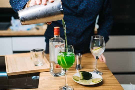 Bottle of Beefeater London Dry Gin sits beside glass of green liquid on red background. neon drink aesthetic, emerald green cocktails, fluorescent beverage trends. Warsaw, Poland, 20 November 2025