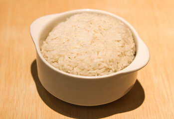 Simple bowl of Steamed White Rice, displayed on a wooden background.
