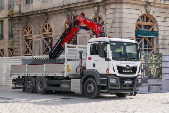 Nancy, France - March 24th 2026 : View on a white dump truck MAN TGS 26.430 with a Fassi crane F215 for a lifting on a construction site with an old building in the background.
