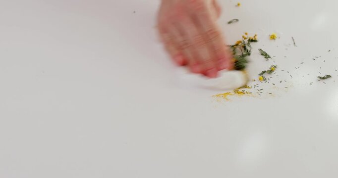 woman clears away flower plant waste from white table after making a bouquet. close-up