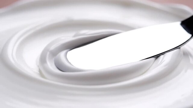 Smooth white cream texture with a swirl and a tool