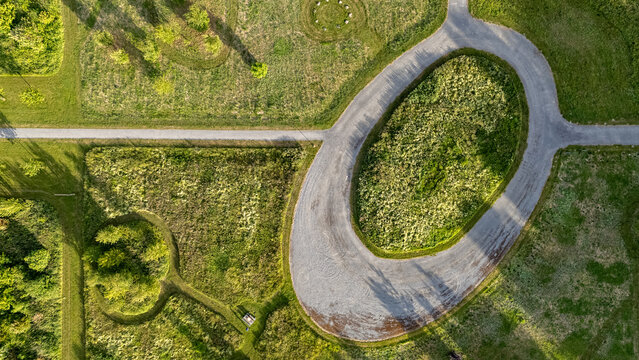 Aerial view of a tranquil landscape unfolds with geometric precision, where circular patterns and straight pathways intersect amidst verdant fields, De Kiem, Flevoland, Netherlands.