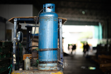Fototapeta premium Gas cylinder industrial warehouse blue metal equipment safety storage tank workplace Blue metal gas cylinder industrial warehouse equipment with soft focus background creating moody atmosphere