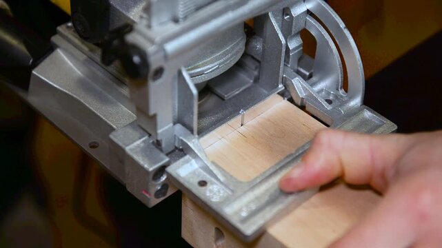 Wood lamella router in action cutting into a wooden surface. The spinning bit carves a precise groove as the attachment cutting into the material.