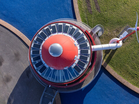 Aerial view of the captivating red and grey structure amidst a vibrant blue playground and green grass, Arthurstraat, Cascadepark, Flevoland, Netherlands.
