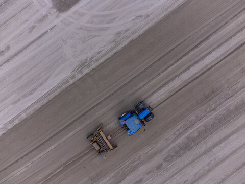 Aerial view of a blue tractor leaving tracks in the snow covered ground, Almere, Flevoland, Netherlands.