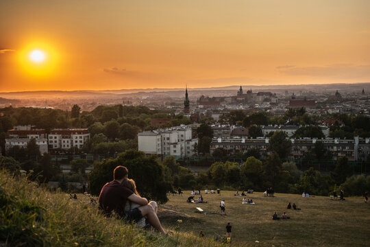 people at sunset admiring the panorama of Krakow from the Krak Mound