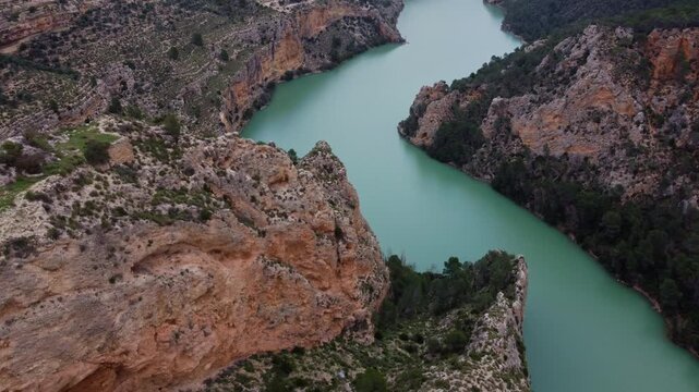 Fast 4K drone dive following a steep canyon cliffside. Exciting cinematic proximity flight over the turquoise J&uacute;car River and rugged limestone formations in Castilla-La Mancha, Spain.