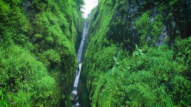 Stable shot of Satsada waterfall flowing between green narrow valley in Raigad District, Maharashtra, India. 4K Aerial view of waterfall cascade in Sahyadri hills. Nature background. Travel, holidays 