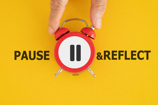 hand holding red clock with stop sign and pause reflect text on grunge yellow background