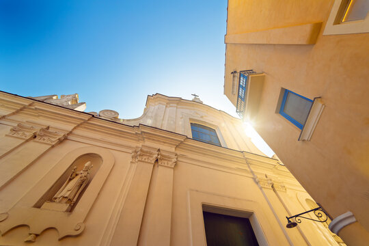 Bright sunny day in Capri, Italy with colorful buildings and historic architecture. Beautiful baroque-style church is surrounded by vibrant yellow facades, balconies under clear blue sky