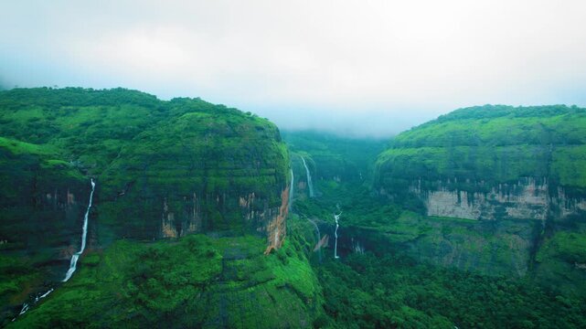 4K Aerial view of Ring waterfall and Devkund waterfall as seen from Savlya Ghat view point in Maharashtra, India. Waterfalls flowing in lush green Sahyadri hills during rainy day in monsoon season.
