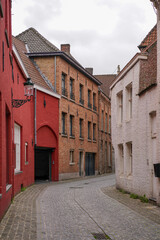 Fototapeta premium Picturesque narrow cobblestone street with red and white brick houses in historic Bruges, Belgium.