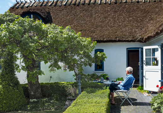Senior man spending leisure time sitting on chair in front yard