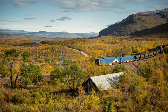 Scenic view of coal train winding through lush greenery against sky