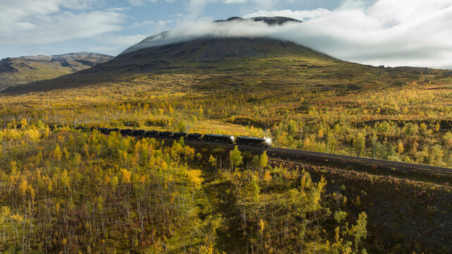 Distant view of coal train moving on track overlooking hill at sunny day