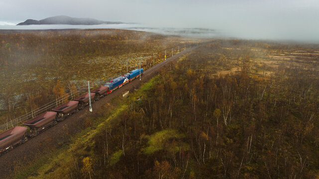 Drone shot of freight train moving on track amidst green landscape