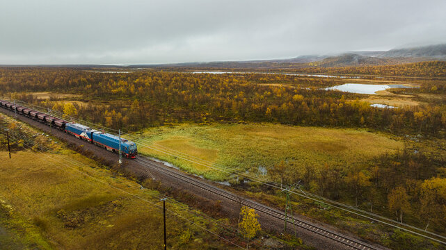 Drone shot of coal train moving on track overlooking green landscape against sky