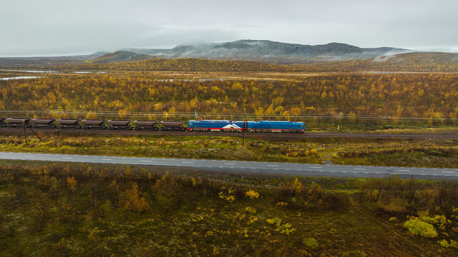 Scenic shot of freight train shipping coal while moving on track amidst green landscape