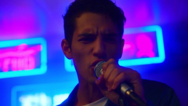Tracking shot of singer performing into microphone in neon nightclub interior handheld dolly forward close up on vocalist face