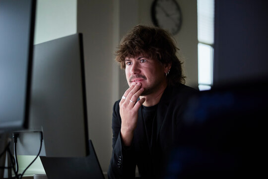 Thoughtful male business expert working on desktop PC in tech office