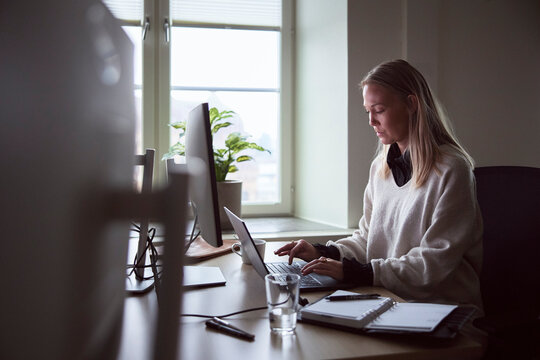 Female tech expert using laptop while working at desk in office