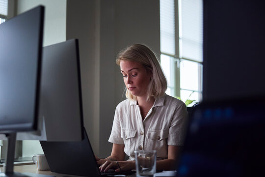Short haired female business professional working on laptop in office