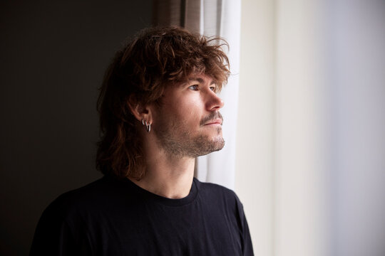Contemplative male entrepreneur with long hair looking away