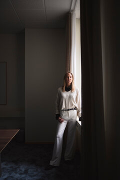 Full length of confident female business expert standing near window in office