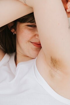 Smiling confident young woman showing armpit hair