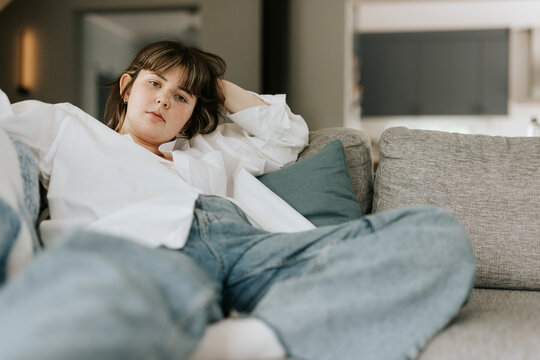Portrait of beautiful young woman posing while sitting on sofa at home
