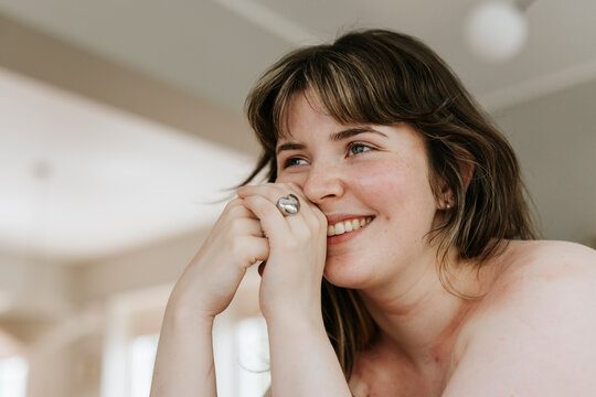 Smiling shirtless young woman with bangs looking away