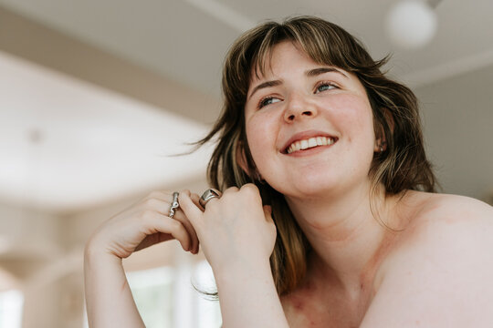 Low angle view of smiling shirtless young woman looking away