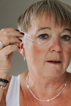 Portrait of mature woman applying face serum with pipette
