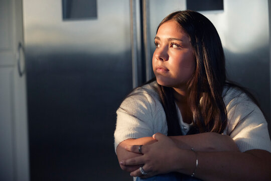Anxious teenage girl looking away while sitting at home