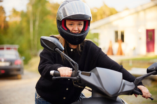 Portrait of girl wearing helmet and pushing scooter