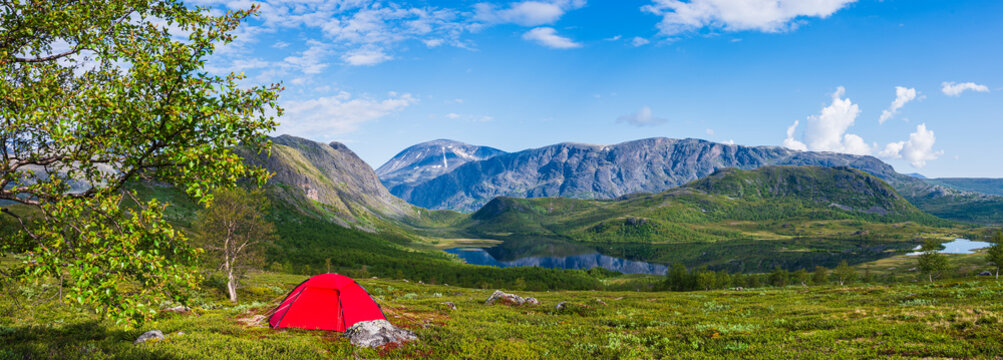 Panoramic view of scenic landscape with tent on grassy land against cloudy sky
