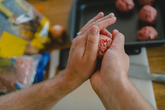 Hand of man making meatball in kitchen at home