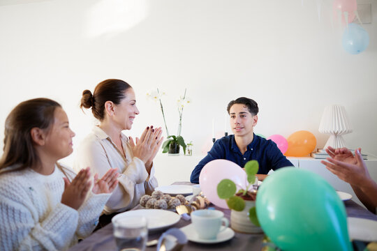 Family celebrating birthday of boy while sitting around dining table at home