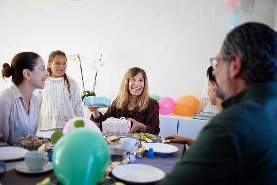 Happy aunt receiving gifts from family members during birthday celebration at home