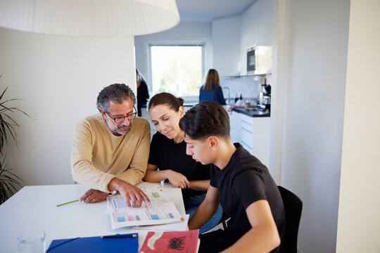 Father and mother helping their son in his studies at home