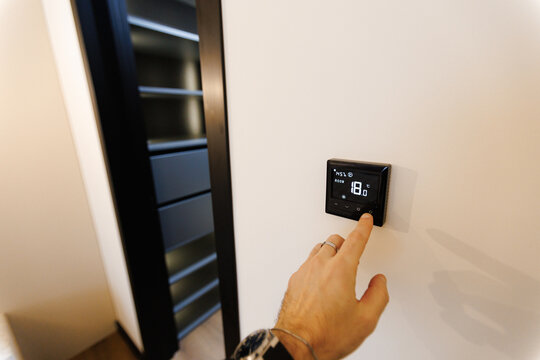 Individual modifies temperature setting on digital thermostat screen